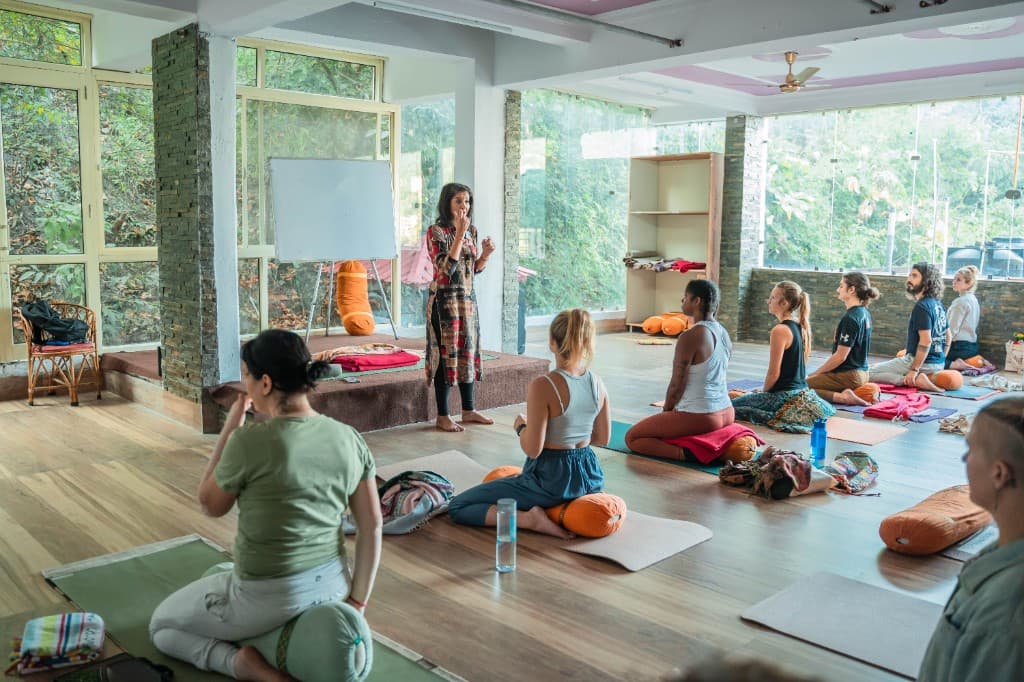 Eine Lehrerin leitet eine kleine Yoga-Gruppe in einem hellen Übungsraum